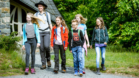 Kinder gehen mit Rangerin im Wald spazieren