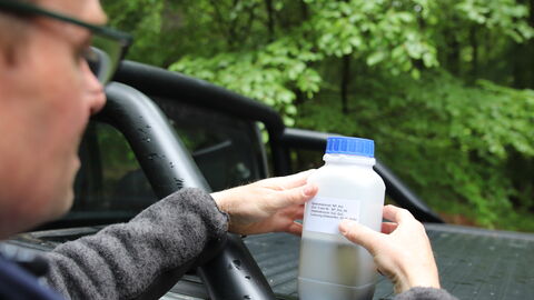 Mensch klebt Etikett auf Plastikbehälter