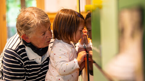 Kind und älterer Mensch entdecken interaktive Ausstellung in der Kellerwalduhr