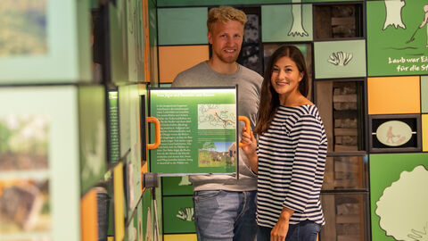 Zwei Menschen ziehen an Ausstellungselement in Kellerwalduhr