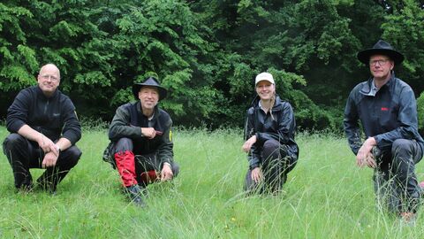 Gemeinsam für die Wildnis von morgen Vier Personen hocken auf einer Wiese