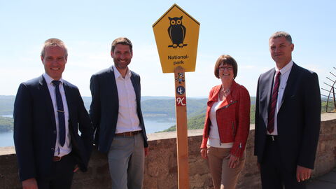 Personen stehen neben Schild mit Eule darauf.