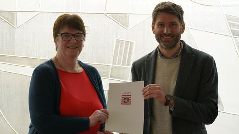 Zwei Personen halten eine Urkunde hoch