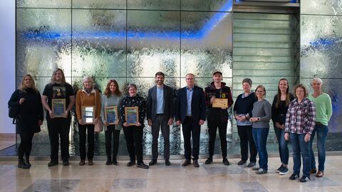 Mehrere Menschen stehen vor einer Wasserwand