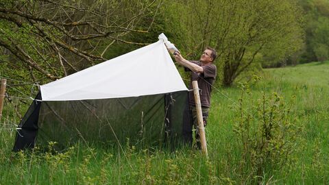 Forscher prüft Insektenfalle auf einer Wiesenfläche