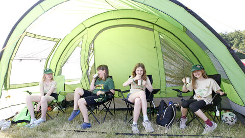 Mehrere Kinder sitzen in einem Zelt und trinken aus Tassen