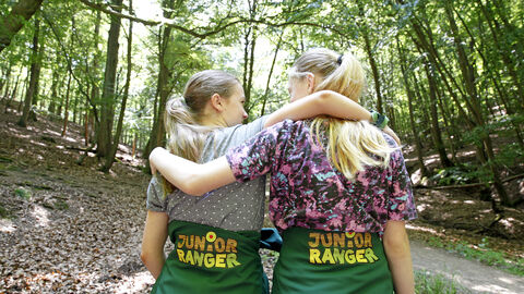 Zwei Kinder stehen mit dem Rücken zur Kamera und umarmen sich