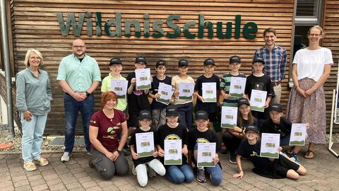 Kinder und Erwachsene stehen gemeinsam für ein Gruppenfoto vor der WildnisSchule