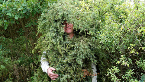 Ein Mensch trägt ein Kostüm aus Wacholderzweigen