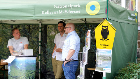 Drei Menschen stehen in einem Info-Pavillon des Nationalparks