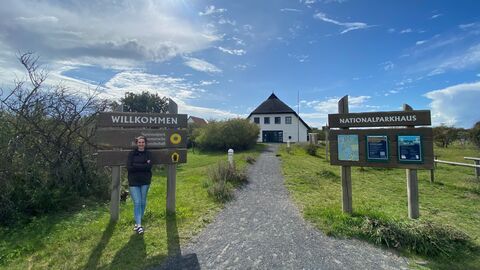 Person steht draußen vor einem Holzschild