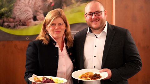 Zwei Personen halten jeweils einen Teller mit Essen in die Kamera