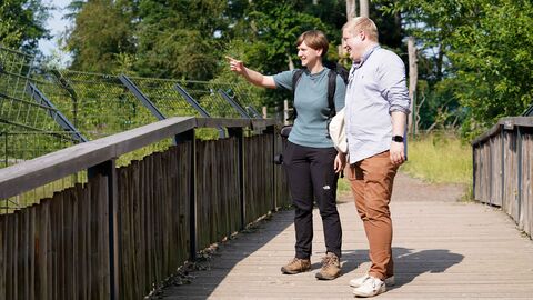 Zwei Personen stehen auf einer Brücke in der Natur
