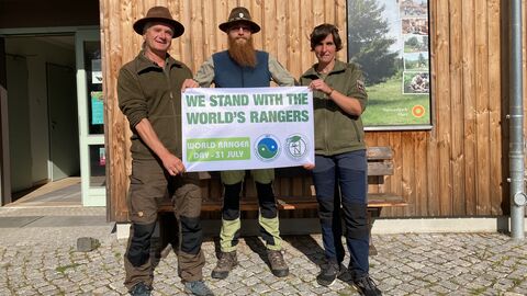 Drei Personen halten ein Plakat hoch