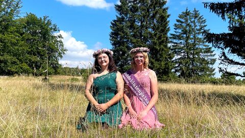 Zwei Heideblütenprinzessinnen sitzen in der Heidelandschaft