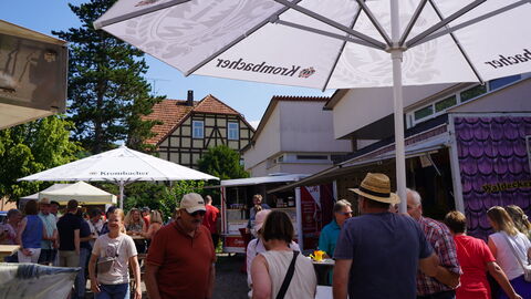 Marktbesuchende Besuchende zwichen den Ständen unter Sonnenschirmen
