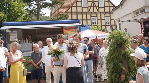Ein Mann und eine Frau gratulieren einer jungen Frau, die mit dem Rücken zur Kamera steht.