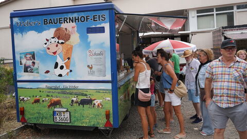 Vor einem Anhänger mit Eis stehen Leute an