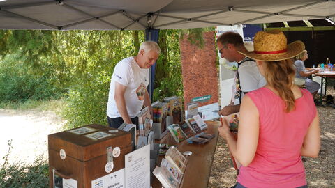 Menschen stehen an einem Stand unter einem Pavillon