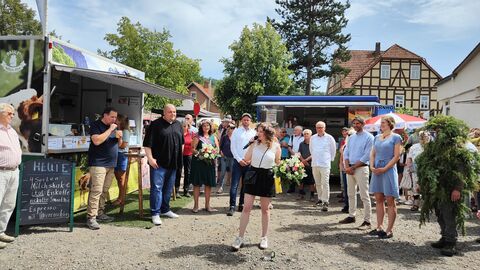 die Heideblütenprinzessin steht mit Mikrofon auf dem Dorfplatz, Menschen drumherum
