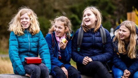 Kinder sitzen im Wald und lachen zusammen